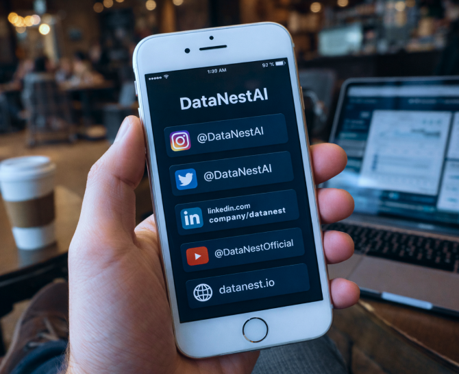 Hand holding iPhone displaying DataNestAI's social media handles for Instagram, Twitter, LinkedIn, YouTube, and website in a cafe setting.