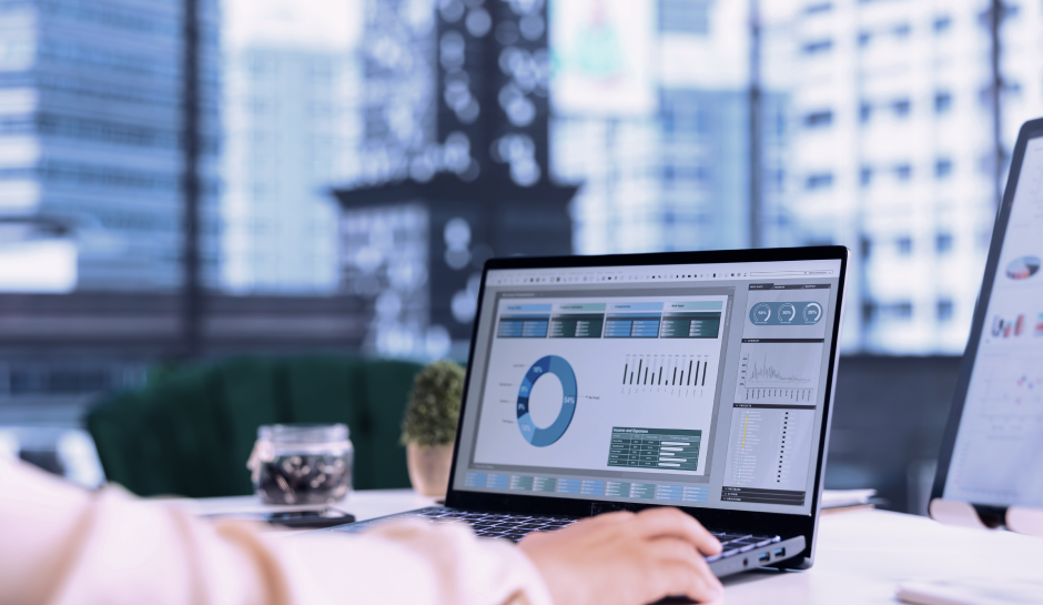 Person working on financial charts and graphs displayed on a laptop screen in a modern office setting.