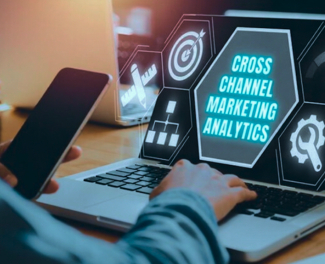Hands on a laptop displaying "Cross Channel Marketing Analytics" with digital icons. A smartphone is held nearby. Modern, tech-savvy atmosphere.