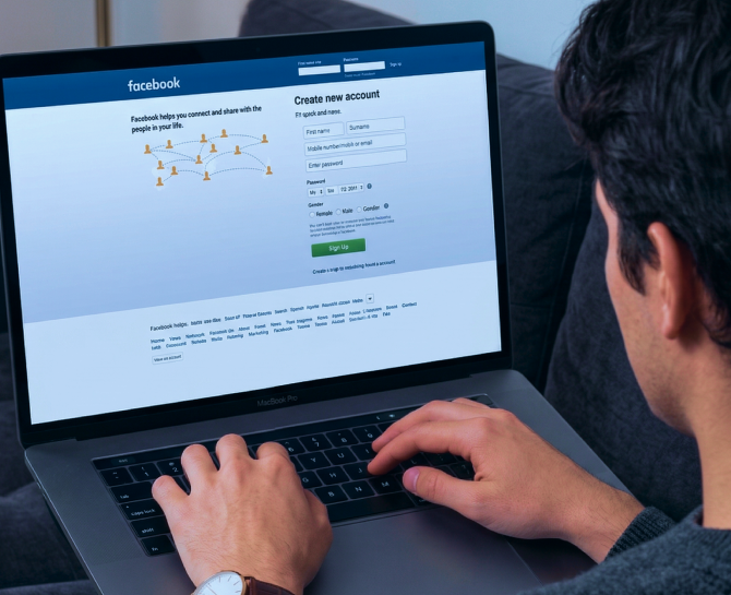 Person using a laptop to access Facebook's sign-up page, preparing to create a new account by entering personal details.